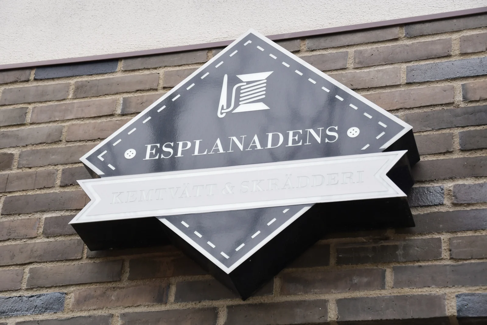 Esplanadens Kemtvätt & Skrädderis skylt på en tegelvägg